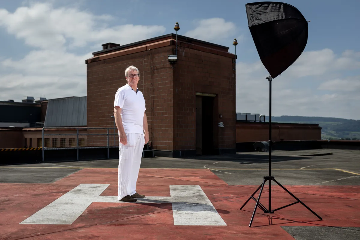 Steht nur für ein Bild im Scheinwerferlicht: Vital Schreiber. Ein Mann in weisser Kleidung steht auf einem Dach auf einem Helikopterlandeplatz, neben ihm ein Lampen-Blitz-Schirm.